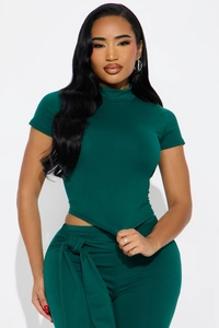 Détail du haut moulant vert foncé avec ourlet asymétrique et pantalon à ceinture nouée