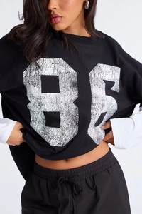 Detail of distressed white 86 number print on black street fashion long sleeve T-shirt
