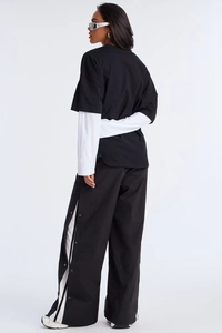 Detail view of streetwear two-piece long sleeve top and side-button wide leg track pants