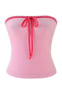 Detail of pink strapless crop top with soft matte texture and decorative lace-up bow
