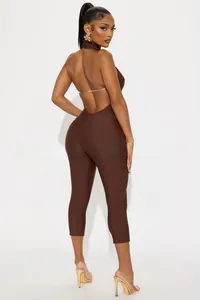 Detail of a brown halter backless jumpsuit with slim-fit stretchy fabric on a female model