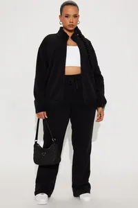 Detailed full-body shot of a black stand-collar zipper track jacket and matching pants set