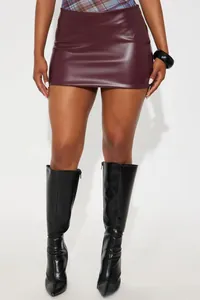 Close-up of wine red PU leather mini skirt with black over-the-knee boots for women