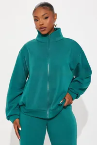Detail of dark teal women's tracksuit showing high collar zip-up hoodie and fabric texture