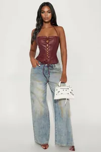 Detail of burgundy PU leather halter corset top with front lace-up and light blue jeans
