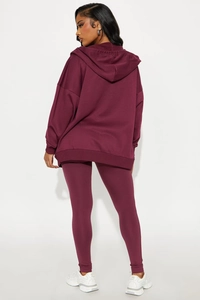 Vue arrière d'un ensemble sweat à capuche bordeaux oversize et legging à taille haute