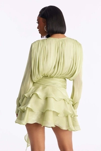 Detailed back view of a light green pleated mini dress with triple-layered ruffle hem