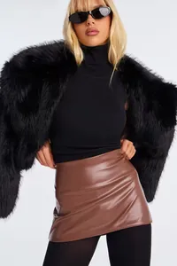 Detail of high-gloss brown PU leather mini skirt with black faux fur shawl and slim top