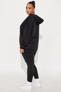 Vue latérale d'un ensemble sweat à capuche noir surdimensionné et legging pour femmes