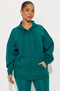 Détail d'un sweat à capuche zippé vert foncé avec cordon réglable et poches avant