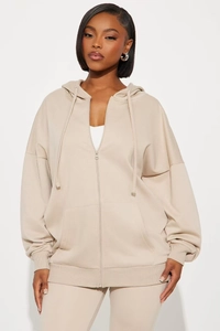 Détail d'un sweat à capuche beige oversize zippé montrant la coupe ample et le tissu doux