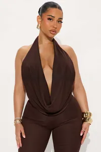Detail of a brown halter neck jumpsuit with deep V-neckline and metallic gold bracelet