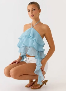Dettaglio di balze azzurre e trama in chiffon plissettato sul top a girocollo aperto
