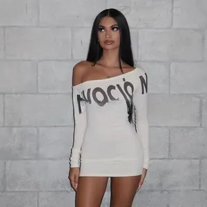 Détail du lettrage NOCIÒN sur une robe courte blanche avec épaule dénudée tendance
