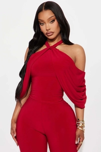 Detail of red halter cross-neck cold-shoulder top and matching high-waisted slim trousers