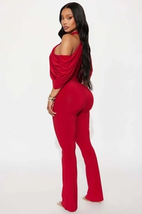 Detail of red halter neck jumpsuit showing ruffled sleeves and flared leg silhouette
