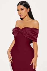Detail of burgundy off-shoulder dress featuring a large satin bow and sleek slim fit