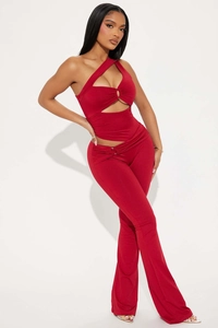 Détail du haut rouge à une épaule, découpes et boucles en métal avec pantalon évasé