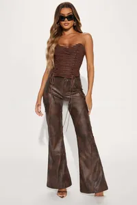 Détail du corset marron à lacets et du pantalon évasé vintage en similicuir