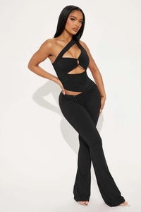 Détail du haut asymétrique ajouré et du pantalon évasé ajusté en tissu noir élégant