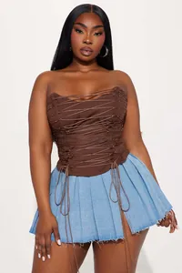 Détail d'un haut corset marron à lacets avec cordon et mini-jupe plissée en jean bleu