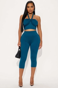 Detail of teal knit two-piece set featuring a halter crop top and high-waisted capris leggings