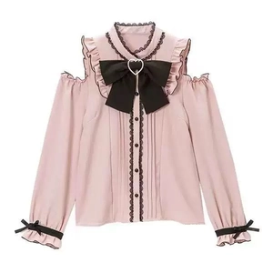Dettaglio della camicetta rosa con spalle scoperte, volant in pizzo nero e fiocco di perle