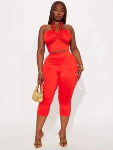 Red two-piece fashion set with criss-cross halter crop top and high-waisted capri pants