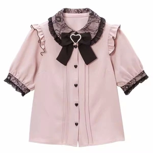 Dettaglio della camicetta rosa con fiocco nero, cuore di perla e colletto Peter Pan in pizzo