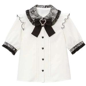 Dettaglio del colletto bianco con pizzo nero, fiocco e accessorio a cuore di perle