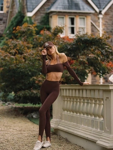 Détail d'un ensemble de yoga marron foncé avec haut à épaules nues et legging à étriers