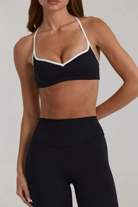 Détail du soutien-gorge de yoga dos nu noir avec liseré blanc et legging taille haute