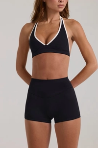 Dettaglio completo del set sportivo nero con bordi bianchi, top all'americana e pantaloncini