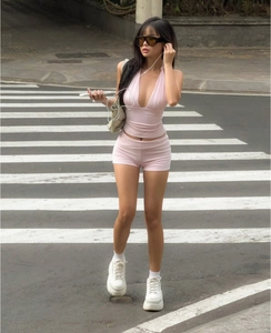 Detail of pink knitted yoga set with halter neck top and high-waist shorts on street
