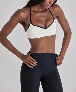 Détail de brassière yoga crème avec bordure noire contrastée et fines bretelles en V