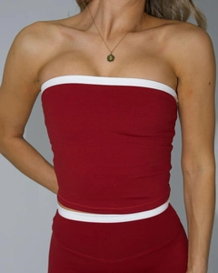 Detail von rotem Sport-BH und Shorts-Set mit weißem Rand und Halskette mit S-Anhänger