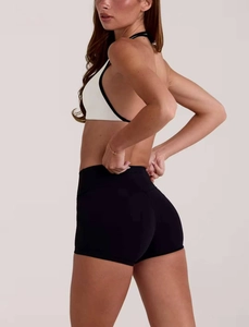 Dettaglio del reggiseno yoga bianco con bordo nero e pantaloncini fitness neri a vita alta