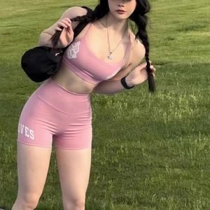 Detailed view of pink sports yoga set with high waist shorts and racerback bra on grass