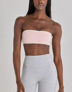 Detail of pink strapless sports bra with white contrast trim and high-waisted gray leggings