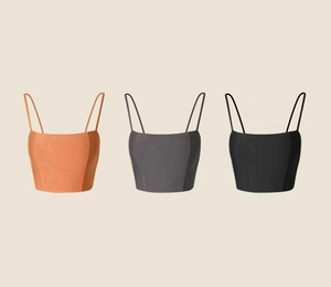 Close-up of three spaghetti strap yoga crop tops in orange-brown, dark grey and black