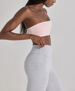 Side view of pink strapless sports bra with white trim and grey high-waist yoga leggings