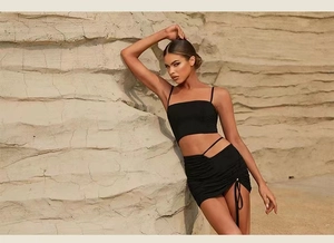Detail of black sports yoga set featuring lace-up mini skirt and thin strap crop top