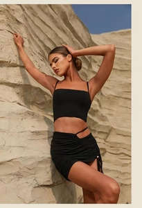 Detail of black yoga set with crop top and side drawstring ruched mini skirt on rock background