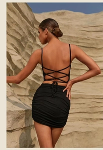 Close-up of black backless yoga set with lace-up straps and ruched skirt detailing