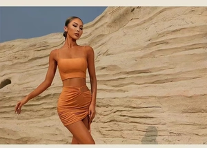 Detail view of orange sports set featuring ruched skirt with side cutout in desert setting