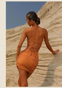 Detail of cross-back strap top and ruched mini skirt in orange elastic knit fabric