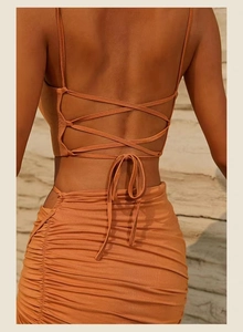 Detail of burnt orange yoga set featuring cross back straps and ruched textured skirt