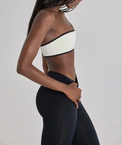 Detail view of white sports bra with black contrast piping and high-waist yoga leggings