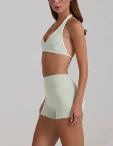Dettaglio del set da yoga verde menta con top allacciato al collo bordato di bianco e pantaloncini
