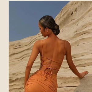 Orange backless yoga set with crisscross straps and ruched long skirt in a desert setting